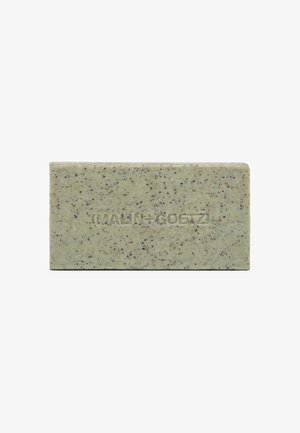 Grüne Seife in Blockform mit glatter Textur, durchzogen von dunklen Sprenkeln, trägt den eingeprägten Markennamen auf einer Seite und hat rechteckige Form.