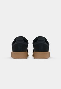 Black suede sneakers with a textured back, gum rubber sole, and subtle stitched accents. The design features a low profile and padded collar.