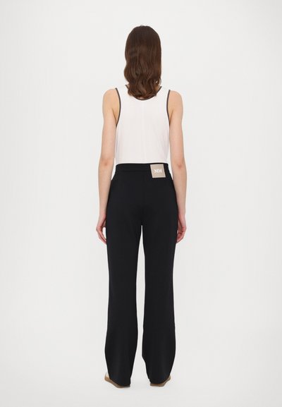 Melni plataji bikses ar augstu jostasvietu, kas aizmugurē rotāta ar mazu etiķeti. Modelis valkā baltu bezpiegu topu. Gluda auduma tekstūra.