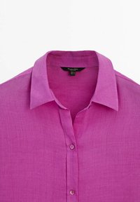 Camicia di lino fucsia con chiusura a bottoni e colletto a punta. Presenta una superficie testurizzata e un peso leggero per favorire la traspirabilità.