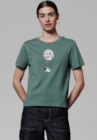 Groene katoenen T-shirt met een ronde halslijn, met een grafisch ontwerp van een astronaut en een maanvormige ballon. Korte mouwen, eenvoudig ontwerp.