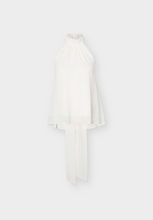 Haut blanc sans manches à col montant froncé et longues attaches en tissu pendantes dans le dos sur fond uni.