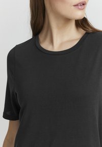 Crna kratka majica s kratkim rukavima i zaobljenim izrezom, s glatkom teksturom i minimalističkim dizajnom.