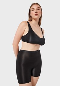 Schwarzer nahtloser BH und hochgeschnittene Shorts mit glatter Textur. Der BH verfügt über breite Träger und einen tiefen V-Ausschnitt, der ein minimalistisches Design bietet.