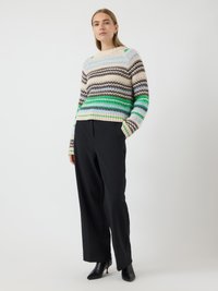 Gebreide trui met meerkleurige strepen in bruin, groen en blauw; brede ribbelzoom en manchetten. Gecombineerd met hoge zwarte broeken.