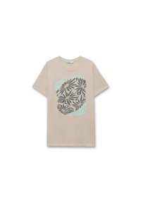 Camiseta de algodón beige con un gráfico floral circular en verde oscuro y azul claro, con el texto "CONCEPTOS DE LA NATURALEZA FLORES." Mangas cortas.