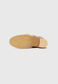 Sandal cu talpă din plută, cu un superior din piele roz, având o curea lată și o talpă texturată pentru aderență. Proiectat pentru purtare casuală.