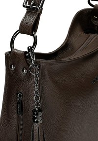 Bruine leren handtas met textuur, metalen ring, kettingtassel, ritsvak en verstelbare schouderband.