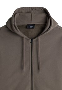 Sudadera con cremallera de color marrón, con una gran capucha suave, cordones y un forro interior de felpa. Incluye una etiqueta de marca en el cuello.