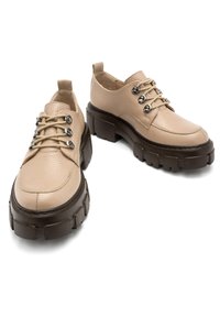 Beżowe skórzane buty z okrągłymi noskami, z fakturowaną cholewką, ciemnymi gumowymi podeszwami i srebrnymi oczkami na sznurówki. Masywna konstrukcja.
