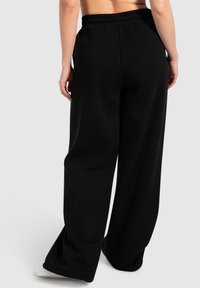 Sorte brede sweatpants i tekstureret stof, med elastisk talje og sidelommer, der har en afslappet pasform og en flydende form.