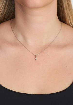 Hõbedast kettkaelakee, millel on väike risti ripats. Kett on õhuke ja ripatsil on läikiv viimistlus. Must taust üleval.