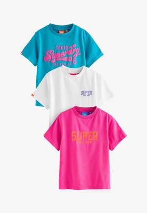 Tre T-shirt: turchese con testo rosa, bianca con logo viola e rosa con testo arancione. Tutte sono a maniche corte e in cotone.