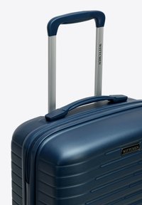 Valigia rigida blu con scanalature orizzontali, accessori neri, doppie ruote e manico telescopico. Nome del marchio "WITTCHEN" visibile.