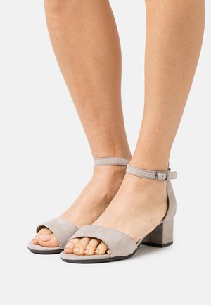 Sandales à talons gris en daim avec orteils découverts, large bride avant, bride de cheville avec boucle et talon carré. Texture lisse et design minimaliste.