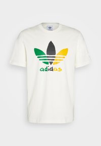 Krémové bavlněné tričko s vícebarevným logem Adidas v zelené, černé, žluté a bílé barvě. Krátké rukávy, design s kruhovým výstřihem.