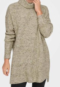 Strickpullover mit hohem Kragen, hellbeige Farbe, strukturiertem Muster und langen Ärmeln; reicht bis zur Mitte des Oberschenkels und hat seitliche Schlitze.