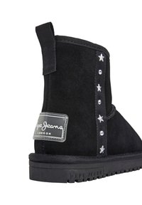 Stivale alla caviglia in suede nero con decorazioni in argento a forma di stella e borchie, linguetta nera, etichetta con marchio sul tallone e suola spessa con motivo.