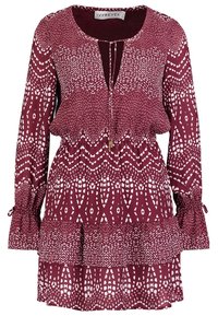 Bordeaux-mønstret kjole med lange ærmer, v-hals og rynket kant. Stoffet har hvide geometriske designs og bånd ved manchetterne.