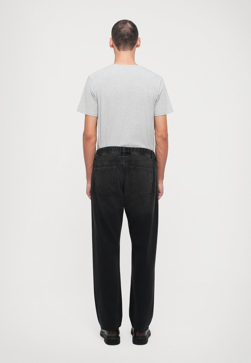 Gray short-sleeve t-shirt paired with black denim pants featuring a loose fit, elastic waistband, and two back pockets.