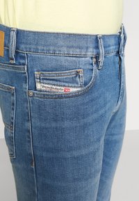 Blå denimjeans med en diskret tvättningseffekt, med en läderlapp i midjan och en märkesetikett på bakfickan.