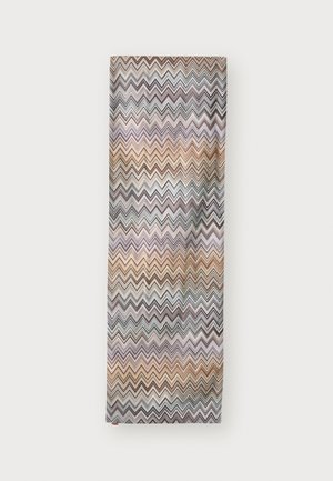Tessuto rettangolare con motivo a zigzag multicolore in tonalità di marrone, beige, nero e viola tenue su uno sfondo bianco.