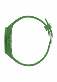 Grön silikon klocka med rund urtavla, texturerat armband och spänne i silver. Har en kontrasterande urtavla och enkla siffermarkeringar.