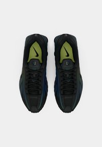 Scarpe da ginnastica nere con accenti verdi e blu. Presentano una tomaia in mesh e materiale sintetico, lacci e logo Nike sulle linguette. Suola in gomma testurizzata.