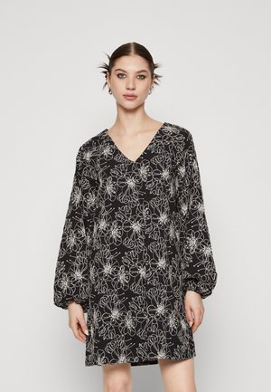 Robe noire avec un décolleté en V et de longues manches bouffantes, arborant un motif floral blanc et une coupe ample, réalisée dans un tissu léger.