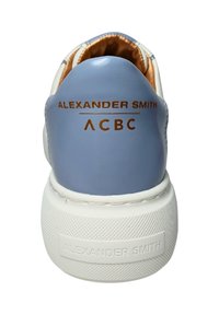 Sneaker bassa in azzurro chiaro con suola in gomma bianca. Presenta una texture liscia e un marchio dorato sul tallone. Interno foderato in arancione.