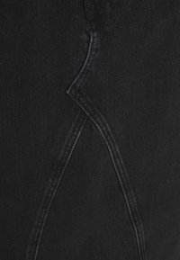 Tecido de denim preto com um design de costura distinto, apresentando uma linha curva. A textura parece suave com um leve brilho.