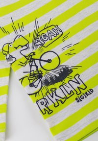 Kurzarmhemd mit grünen und grauen Streifen, das einen Dinosaurier auf einem Fahrrad zeigt, mit dem schwarzen Druck "YEAH" und "RKLIN". Aus Baumwollmaterial.