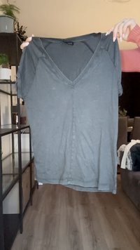 Sivá blúzka s krátkym rukávom a výstrihom do V, s gombíkovým zapínaním na prednej strane, jemnou tkaninou, uvoľneným strihom a mierne oversized strihom.