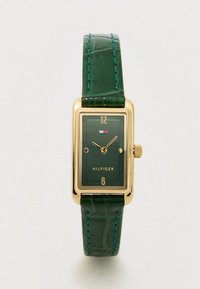 Rectangular gold-tone watch with a green dial, gold accents, and a green croc-embossed leather strap with blue stitching. Brand name: Hilfiger.