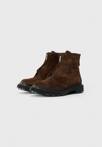 Bottines en daim marron à bout rond, avec un détail de zip à l'avant et une semelle en caoutchouc noir texturé.