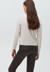 Ljusgrå, långärmad topp med rund halsringning, kort design och mjuk textur, kombinerad med mörkgrå, slim fit jeans.