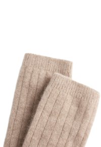 Scaldamuscole beige lavorati a maglia in morbida lana, con una texture a coste e bordi superiori piegati per calore e comfort.