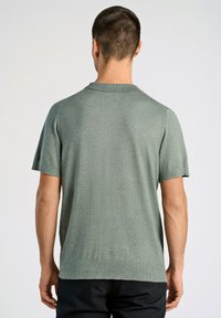 Kortärmad, mossa grön, stickad t-shirt med en slät textur, ribbad krage och manschetter, samt en rak fåll. Diskret melerad mönster synlig.