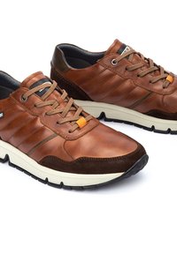 Baskets en cuir marron et en suede avec un design texturé, fermeture à lacets, accents orange et une semelle blanche contrastante.