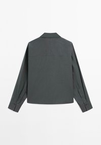 Camicia a maniche lunghe grigio scuro con polsini abbottonati, cucitura della spalla diritta e colletto classico, esposta piatta su uno sfondo bianco.