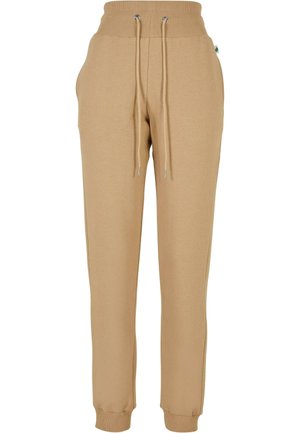 Pantaloni della tuta beige realizzati in tessuto morbido; presentano una vita elasticizzata con cordini, tasche laterali e polsini affusolati.