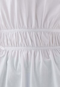 Biały top z materiału z gumką w talii, tworzącym efekt ściągnięcia. Miękka tekstura z gładkim wykończeniem.