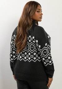 Suéter de punto gris oscuro con un cuello alto, que presenta un patrón geométrico y de copos de nieve en blanco a lo largo del canesú. Tejido texturizado, corte relajado.
