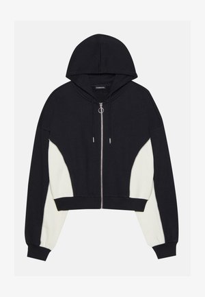 Black and white cropped hoodie with a front zipper, hood, and contrasting side panels. Features silver hardware and ribbed cuffs and hem.