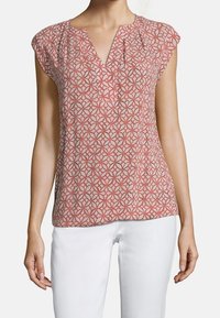 Blusa a manica corta in corallo con un motivo geometrico, presenta un collo a V, dettagli arricciati e un tessuto morbido e leggero.