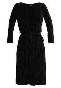 Vestido de terciopelo negro con escote redondo, mangas largas y un cinturón de lazo en la cintura. Presenta un diseño texturizado y fluido.