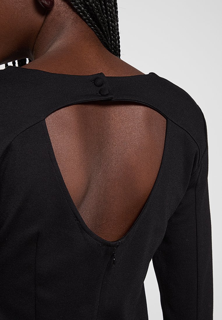 Czarna sukienka z głębokim dekoltem V z otworem w kształcie łezki, dwiema guzikowymi detalami przy dekolcie oraz gładką teksturą materiału.