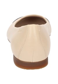 Chaussure plate en cuir beige avec un bout rond et un faible talon. Détails de couture à l'arrière et finition lisse, reposant sur une semelle en caoutchouc beige.