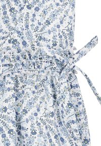Tissu bleu clair avec des motifs floraux en bleu et jaune, avec des détails smockés et un lien sur le côté pour l'ajustement.