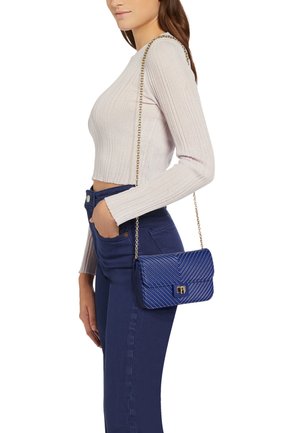 Borsa a spalla blu trapuntata con chiusura dorata e tracolla a catena, caratterizzata da un motivo a zigzag e una superficie liscia.